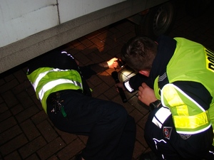 Zdjęcie dwóch policjantów w kamizelkach odblaskowych w trakcie działań w warunkach nocnych