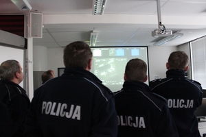 Zdjęcie przedstawiające grupę umundurowanych słuchaczy w sali wykładowej - ujęcie od tyłu - w tle widoczny ekran z wyświetloną prezentacją