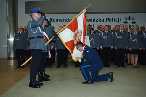 Aula Komendy Wojewódzkiej Policji podczas uroczystości wprowadzenia nowego komendanta widać stojących umundurowanych na galowo policjantów oraz poczet sztandarowy.