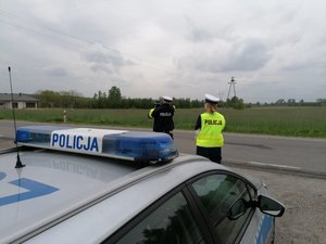 Radiowóz i dwoje policjantów przy drodze.
