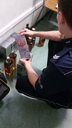 policjant  podczas oględzin zabezpieczonego alkoholu
