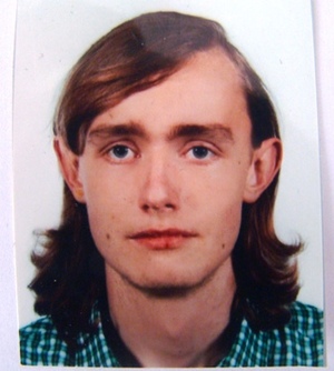 Wizerunek zaginionego, mężczyzna w koszuli w niebieską kratkę, włosy brązowe do ramion.