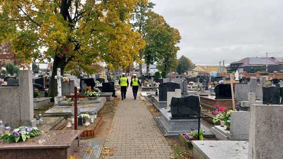 Policjanci spacerują po cmentarzu.