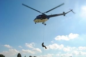 Zdjęcie przedstawiające śmigłowiec i spuszczającego się z niego na linie funkcjonariusza