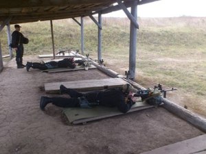 Zdjęcie dwóch uczestników ćwiczeń na stanowiskach strzelnicznych wraz z dowódcą
