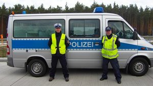 Zdjęcie dwóch umundurowanych funkcjonariuszy niemieckich na tle radiowozu typu van