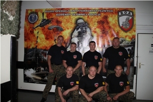 Zdjęcie umundurowanych uczestników ćwiczeń we wnętrzu na tle baneru Biura Operacji Antyterrorystycznych Komendy Głównej Policji