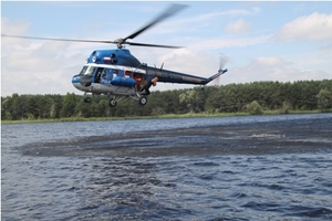 Zdjęcie śmigłowca policyjnego w trakcie lotu nad jeziorem