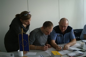 Zdjęcie trojga uczestników zajęć na sali wykładowej przy stole w trakcie części warsztatowej