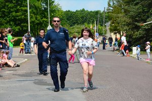 Policjant pomaga dobiec do mety dziewczynce która wzięła udział w kids run.