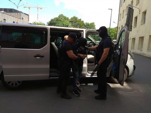 policyjny furgon nieoznakow3any z którego wysiadaja policjanci po cywilnemu i podejrzany