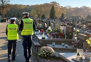 Policjanci spacerują po cmentarzu.