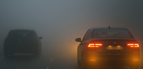 Dwa samochody jeden ze światłami mijania drugi bez.
