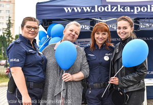Dwie policjantki wraz z dwiema kobietami trzymającymi niebieskie balony na patykach.