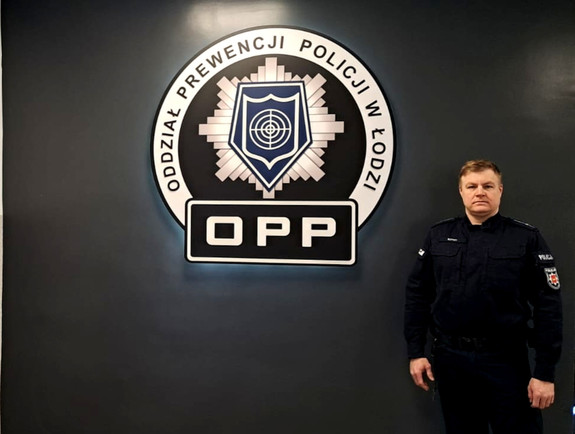 Policjant w mundurze stojący w pomieszczeniu Oddziału Prewencji Policji w Łodzi.