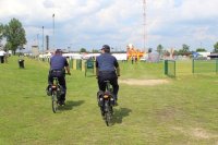 dwóch policjantów jadących na rowerach, którzy patrolują piknik motocyklowy