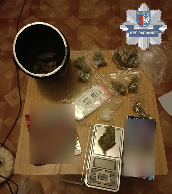 W prawym górnym rogu logo Komendy Powiatowej Policji w Pabianicach. Na stole znajduje się susz roślinny i waga jubilerska.