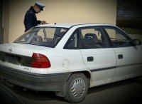 policjant i kontrolowany biały samochód osobowy