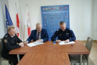 Policjant, strażnik Miejski i Burmistrz Łęczycy podpisują dokument.