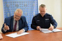 Policjant i Burmistrz Łęczycy podpisują dokument.