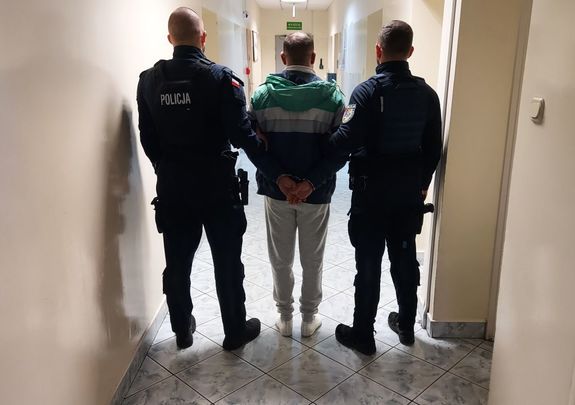 umundurowani policjanci prowadzą zatrzymanego.