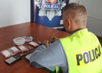 policjant wykonuje oględziny zabezpieczonych narkotyków