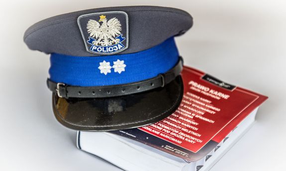 czapka policyjna i książka  - ustawa kodeks karny
