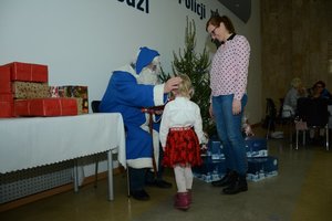 Niebieski Mikołaj daje dziewczynce prezent , obok stoi mama