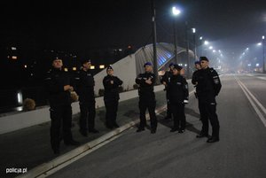 delegaci z policjantami z misji stoja na jednym z most.ów