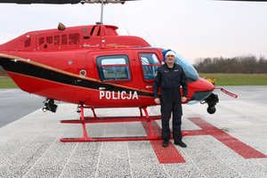 Pilot w czapce mikołaja stoi przy policyjnym śmigłowcu