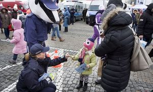 Policjantka podaje dziecku gadżety policyjne.