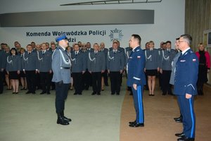 Aula Komedy Wojewódzkiej Policji podczas uroczystości wprowadzenia nowego komendanta widać stojących umundurowanych na galowo policjantów oraz poczet sztandarowy.