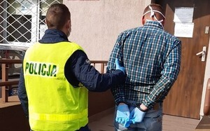 Policjant prowadzi zatrzymanego.