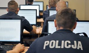 Policjanci siedzą przed komputerami.