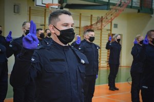 Sala gimnastyczna Oddziału Prewencji Policji w Łodzi, uroczystość ślubowania policjantów, policjanci recytują rotę ślubowania.