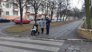 Policjantka stoi i kobiecie z wózkiem z małym dzieckiem i pokazuje odblaskowa choinkę zachęcając do zabrania odblasku.
