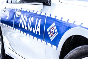 Bok radiowozu z napisem policja i logo ruchu drogowego czyli litera R w rombie.