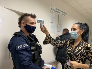 Umundurowany policjant podczas badania temperatury ciała.