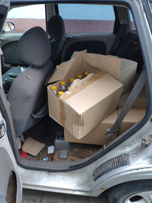 Butelki plastikowe w pudle kartonowym na tylnym siedzeniu samochodu.