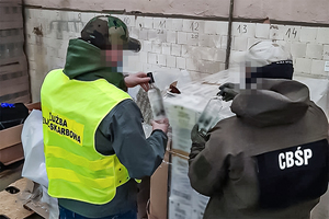 Funkcjonariusze Centralnego Biura Śledczego Policji i Służby Celno-Skarbowej trzymają w rękach nielegalny alkohol.