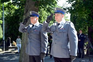 Dwaj umundurowani na galowo oficerowie policji salutują oddając honor.