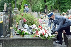 policjant składa kwiaty na grobie