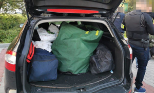 Bagażnik auta wypełniony skradzionymi przedmiotami, widać torby.