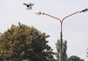 Unoszący się w powietrzu dron obok latarnia uliczna.