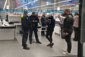 Patrol mieszany policjant ze strażnikiem miejskim legitymują kobietę w galerii handlowej.