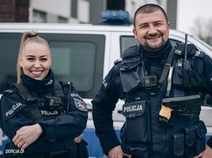 uśmiechnięty policjant i policjant na tle radiowozu