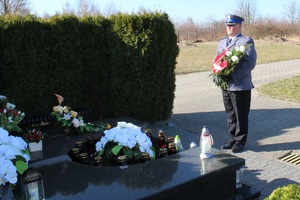 cmentarz w Pabianicach, komendant powiatowy stoi z wiązanką kwiatów nad grobem poległego policjanta