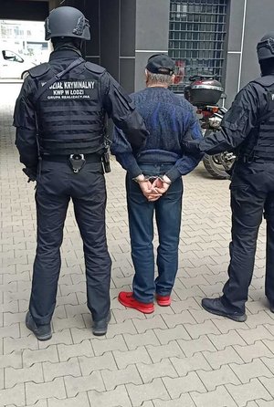 Umundurowani policjanci, którzy maja napis wydział kryminalny na plecach prowadzą zatrzymanego mężczyznę.