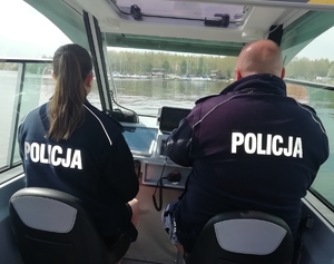 Dwoje umundurowanych policjantów siedzi w łodzi motorowej.