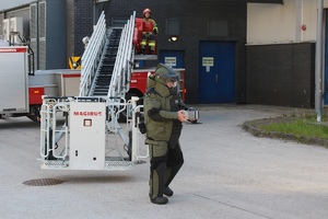 policyjny pirotechnik stoi przed wozem strażackim